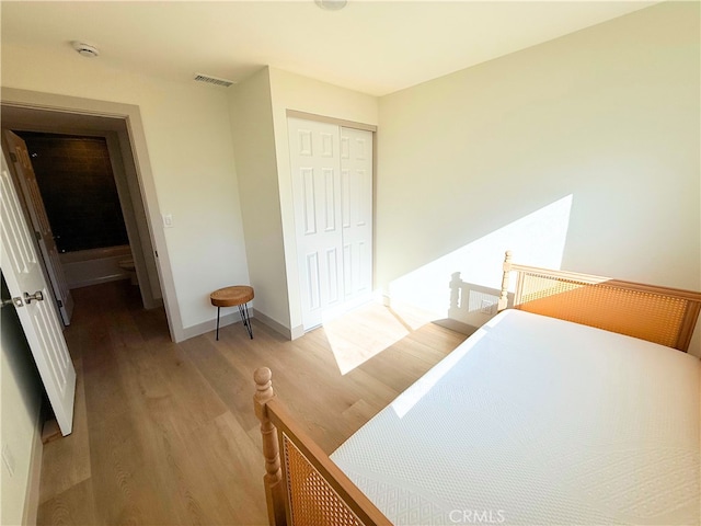 bedroom with baseboards, a closet, visible vents, and light wood-type flooring
