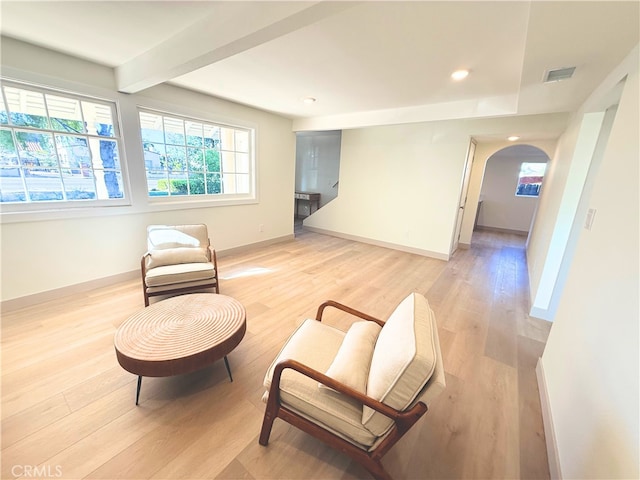 living area featuring arched walkways, visible vents, light wood-style flooring, and baseboards