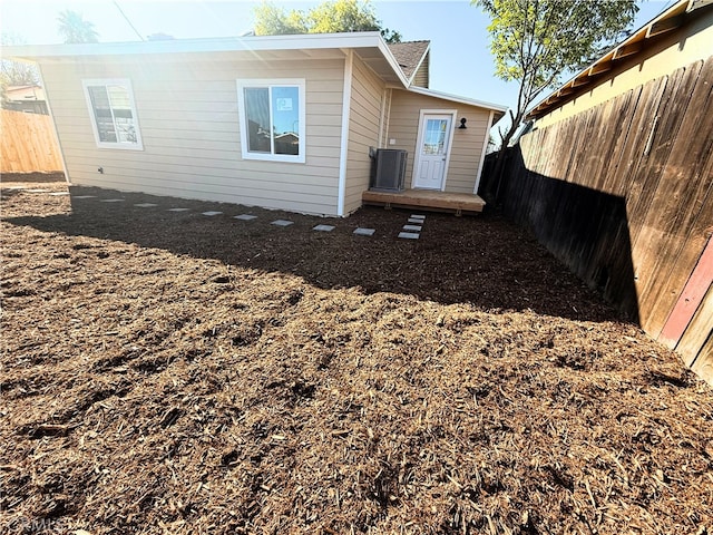 back of property featuring a fenced backyard and central AC