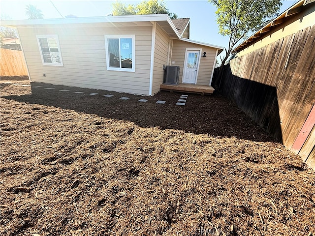 rear view of property featuring central AC and a fenced backyard