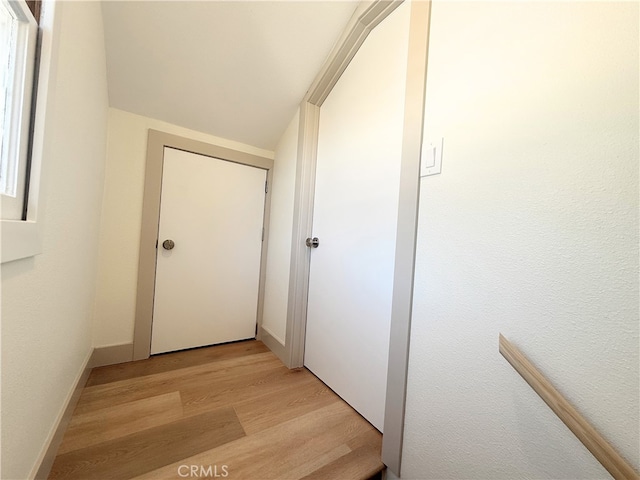 corridor featuring light wood-style flooring and baseboards