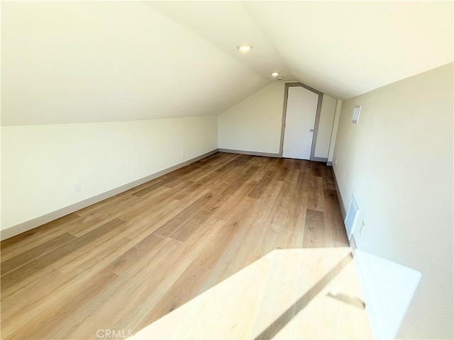 bonus room featuring baseboards, light wood-type flooring, and vaulted ceiling