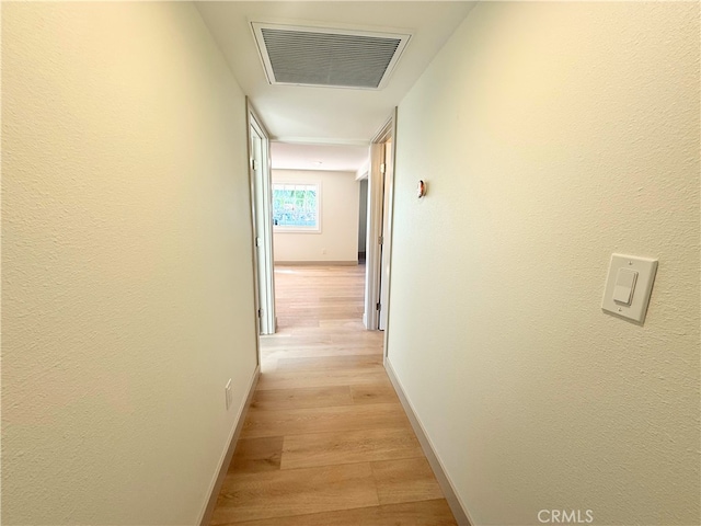 corridor with visible vents, baseboards, and light wood finished floors