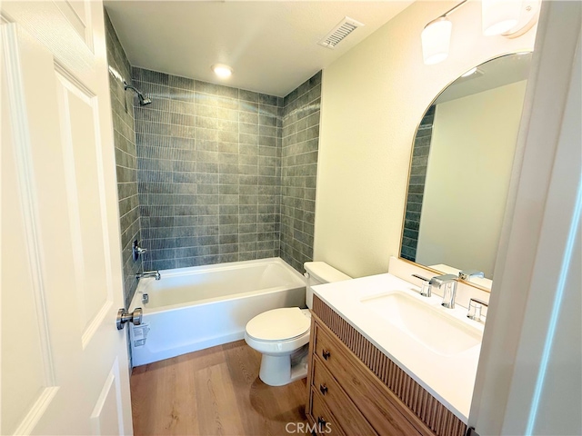 bathroom featuring toilet, tub / shower combination, wood finished floors, visible vents, and vanity