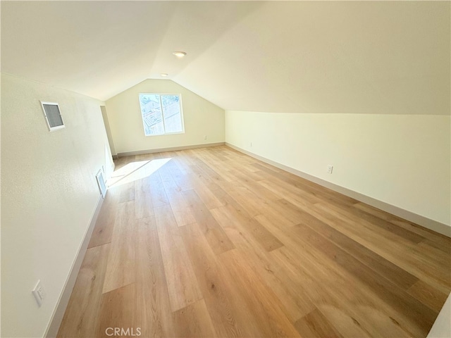 bonus room with lofted ceiling, baseboards, light wood-style flooring, and visible vents