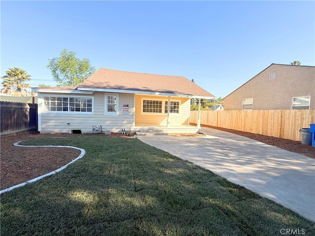 rear view of house with a yard, roof with shingles, concrete driveway, and fence