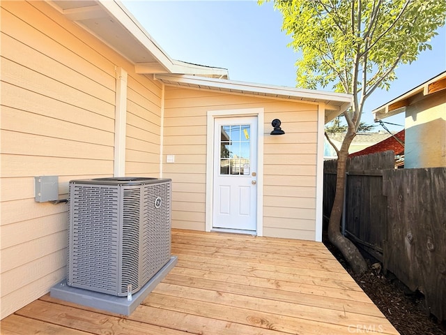 doorway to property with central AC, a deck, and fence