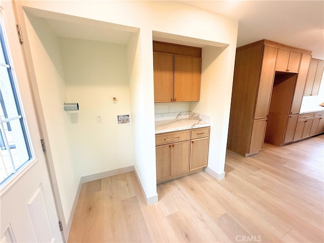 clothes washing area with laundry area, light wood-style flooring, and baseboards