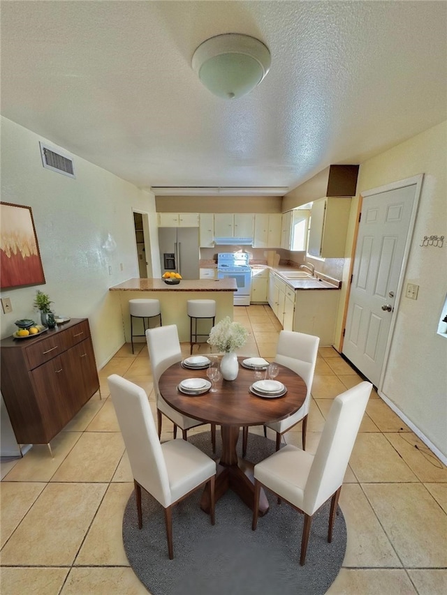 dining room with visible vents, a textured ceiling, and light tile patterned flooring