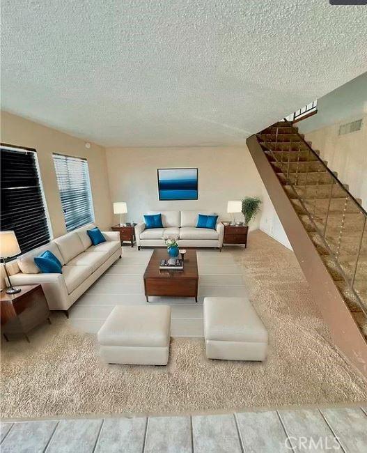 living room with stairway, a textured ceiling, and visible vents