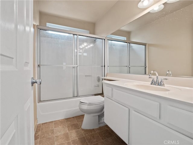 full bath featuring vanity, toilet, and bath / shower combo with glass door