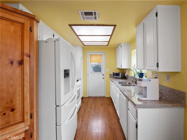 kitchen featuring white appliances, visible vents, a sink, white cabinets, and light wood-style floors