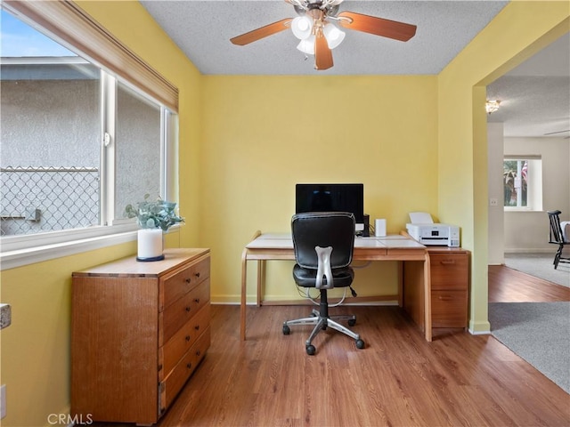 home office with ceiling fan, a textured ceiling, baseboards, and wood finished floors