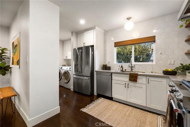 kitchen featuring a sink, white cabinetry, appliances with stainless steel finishes, dark wood-style flooring, and washing machine and clothes dryer