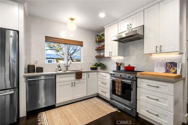 kitchen featuring light countertops, white cabinets, under cabinet range hood, appliances with stainless steel finishes, and backsplash