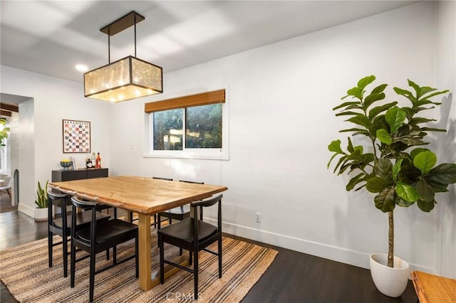 dining space with baseboards and dark wood finished floors