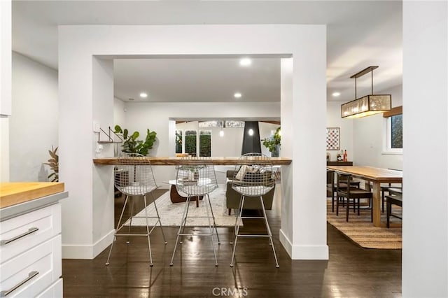 bar featuring dark wood-type flooring, recessed lighting, and baseboards