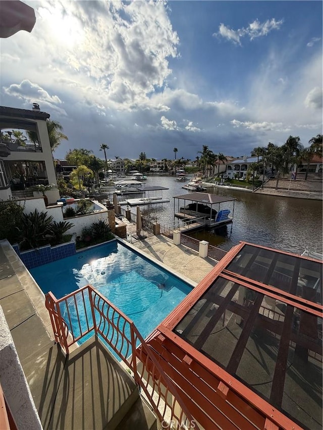 pool featuring a water view, a dock, and a patio area