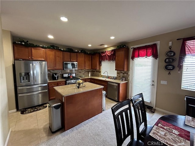 kitchen with decorative backsplash, appliances with stainless steel finishes, a center island, and a sink