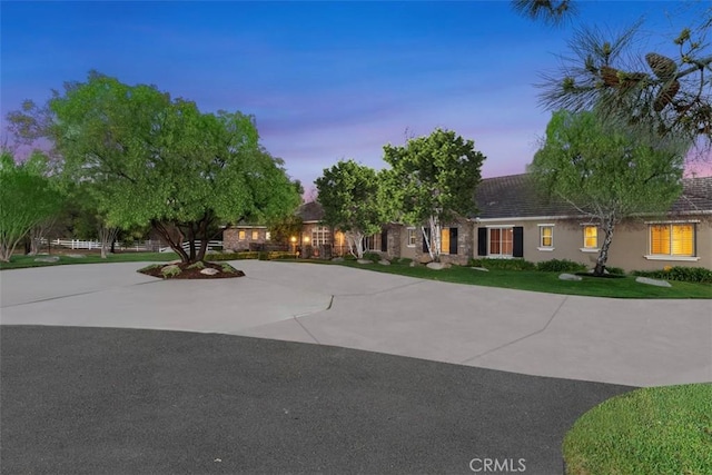 view of front of home featuring stucco siding, curved driveway, and a lawn