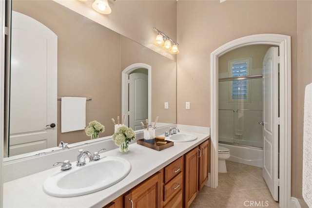 full bathroom featuring a sink, toilet, double vanity, and tile patterned floors