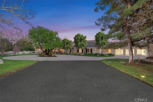 view of front facade featuring curved driveway and fence