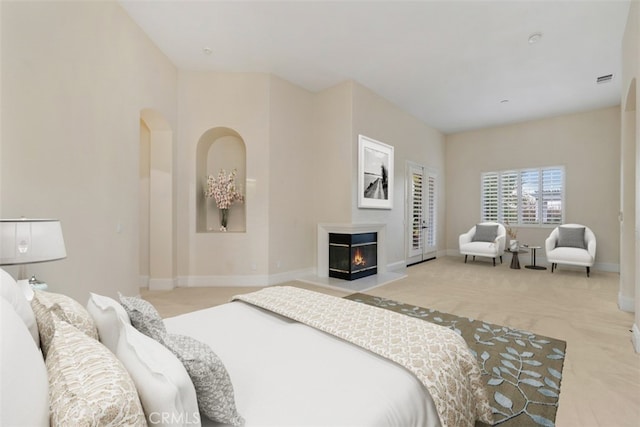 bedroom featuring a glass covered fireplace, baseboards, and carpet floors