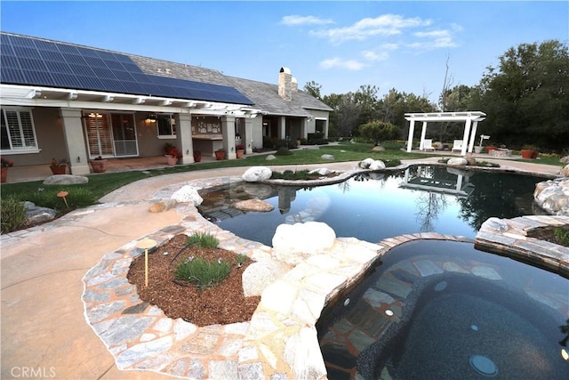 view of swimming pool with a patio area, a pergola, a pool with connected hot tub, and a lawn