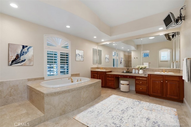 bathroom featuring a bath, recessed lighting, double vanity, and a sink