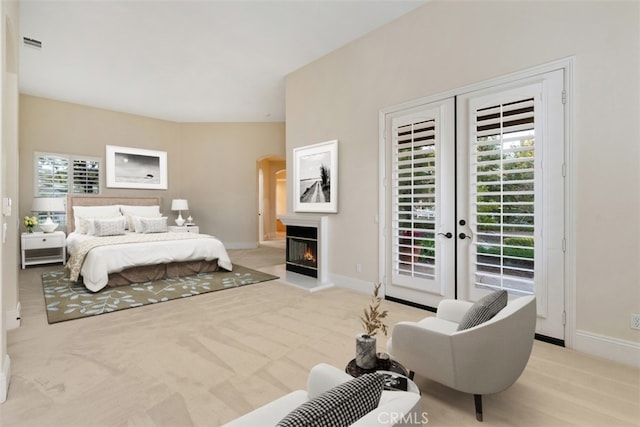 bedroom featuring a glass covered fireplace, baseboards, carpet, and access to exterior