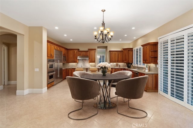 dining space with recessed lighting, baseboards, arched walkways, and a notable chandelier