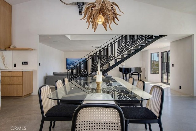 dining area featuring recessed lighting, stairway, concrete flooring, and a towering ceiling