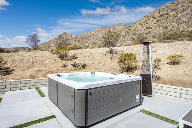 exterior space with a patio area, a mountain view, and a hot tub