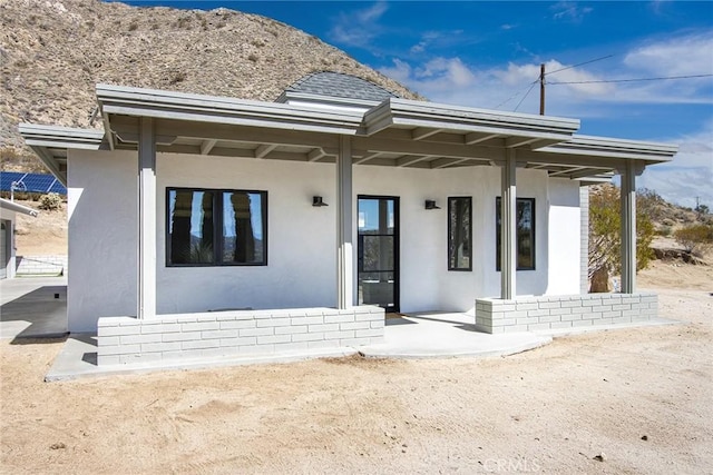 back of property featuring stucco siding and roof with shingles