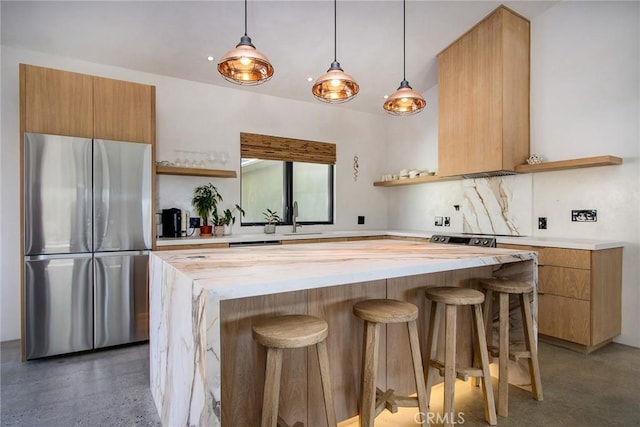 kitchen with a breakfast bar, open shelves, freestanding refrigerator, hanging light fixtures, and modern cabinets