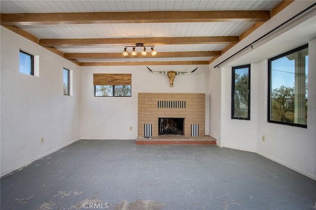 unfurnished living room with beam ceiling, a brick fireplace, and baseboards