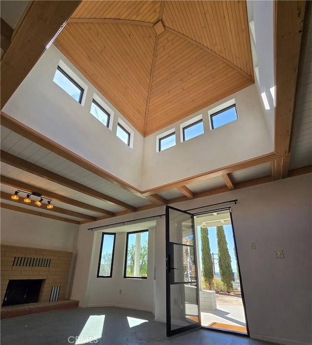 unfurnished living room featuring beamed ceiling, a high ceiling, and a fireplace