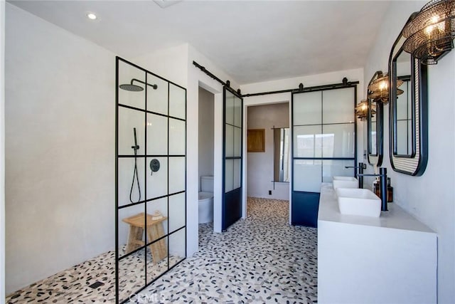 bathroom with double vanity, recessed lighting, a sink, a walk in shower, and toilet