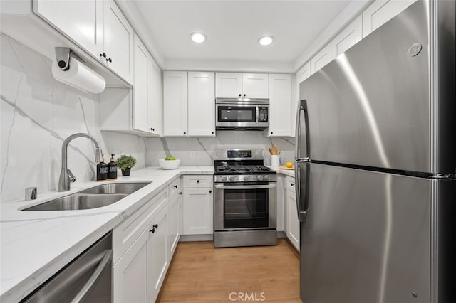 kitchen with white cabinets, light wood-style flooring, appliances with stainless steel finishes, and a sink