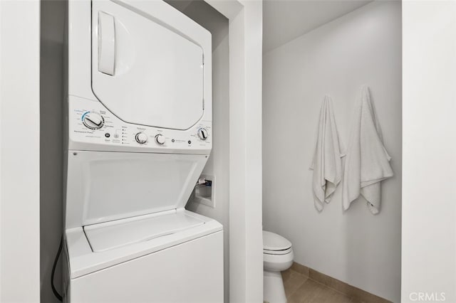 laundry area featuring light tile patterned floors and stacked washer / drying machine