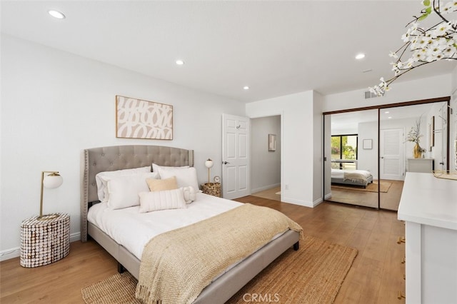 bedroom with recessed lighting, light wood-type flooring, baseboards, and a closet