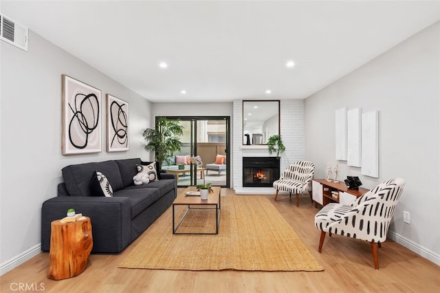 living area with visible vents, a brick fireplace, baseboards, recessed lighting, and wood finished floors