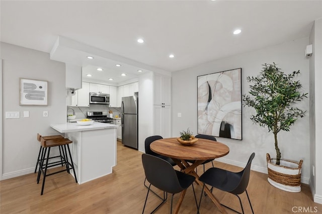 dining room with recessed lighting, light wood-style flooring, and baseboards