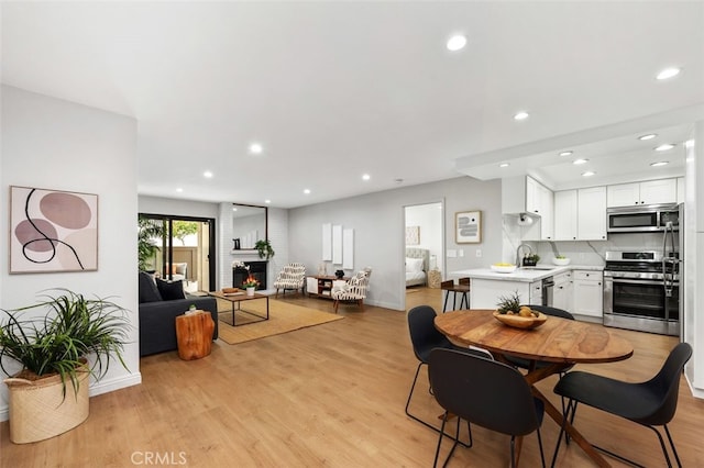 dining area with recessed lighting, a fireplace, and light wood-type flooring