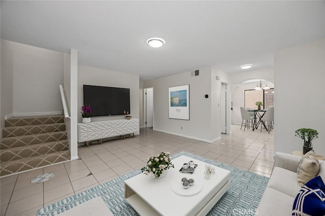 living area featuring tile patterned floors, visible vents, arched walkways, and baseboards