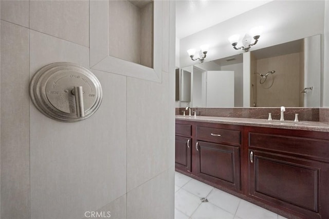 bathroom with double vanity, a shower, tile patterned floors, and a sink