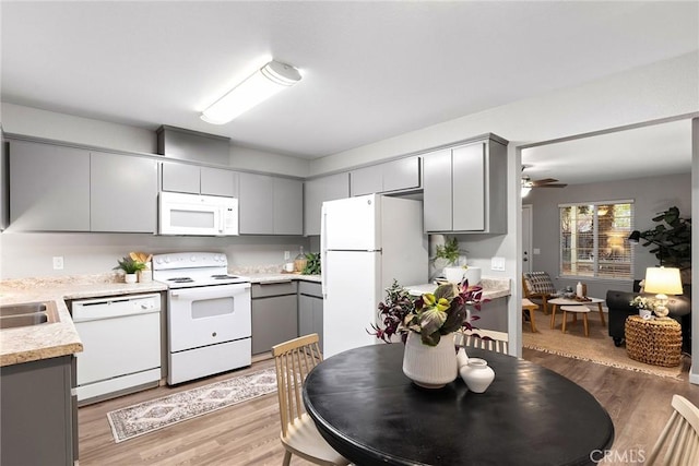 kitchen with white appliances, light wood-style floors, gray cabinetry, and light countertops