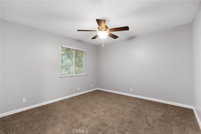 spare room featuring ceiling fan, baseboards, and dark colored carpet