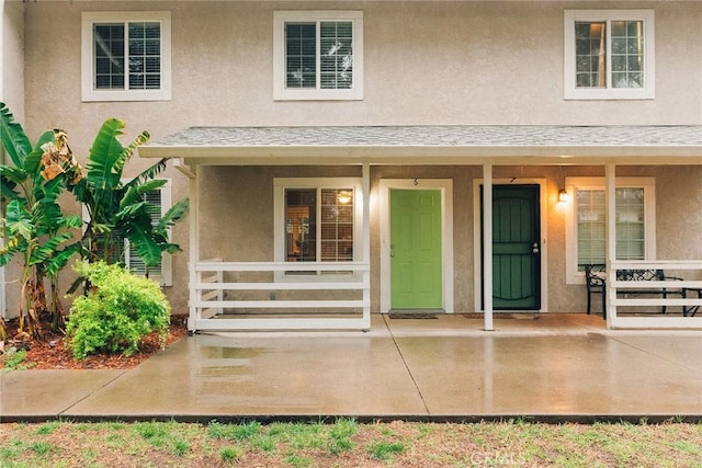 view of exterior entry with a porch and stucco siding