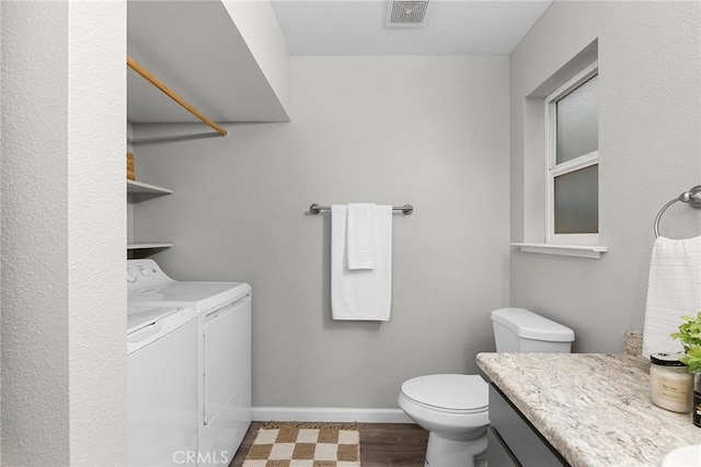 bathroom with visible vents, baseboards, washer and clothes dryer, toilet, and vanity